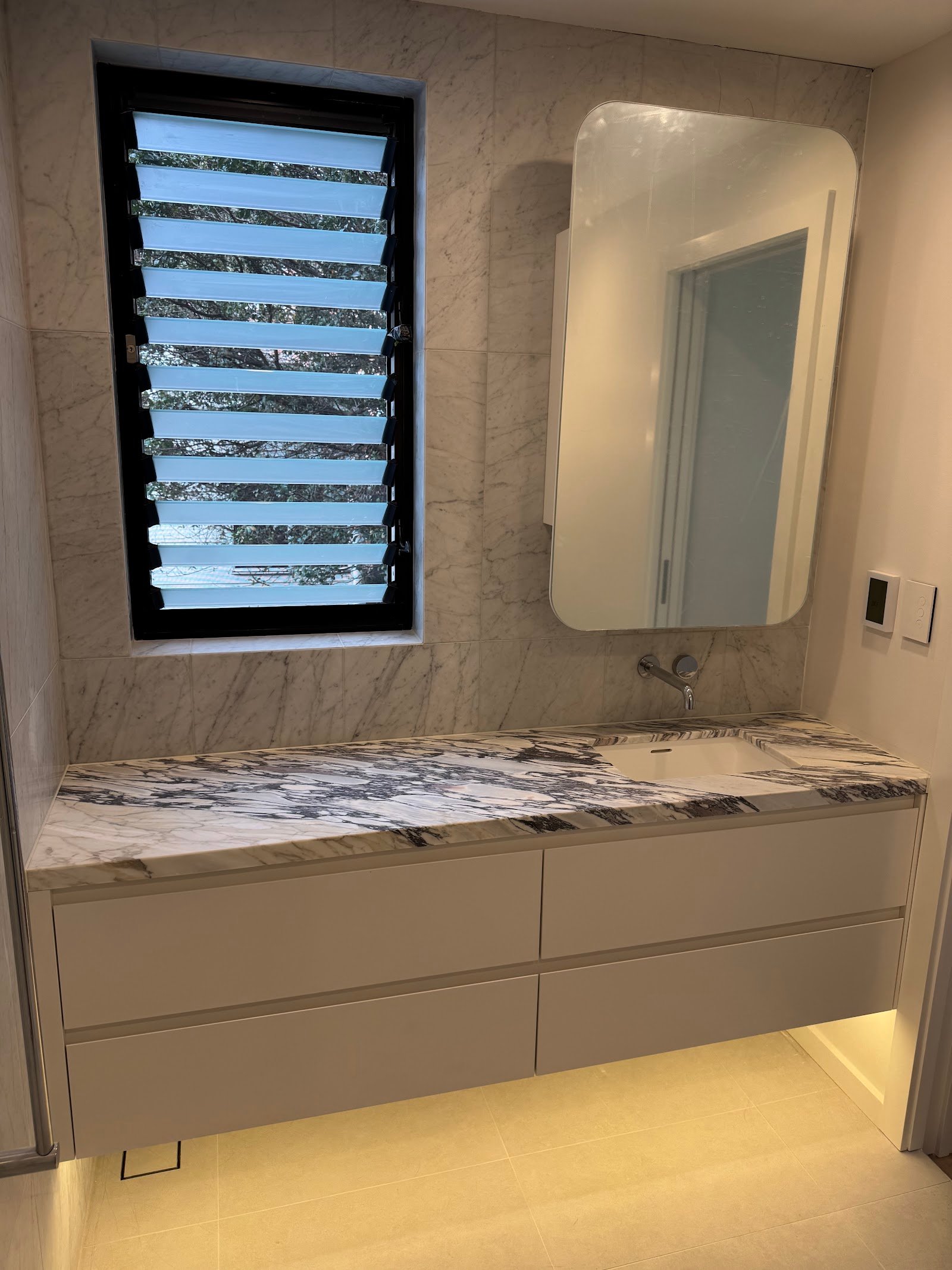 Bathroom at the Fairlight townhouse renovation with marble vanity and black-framed louvre window, Black Willow Group