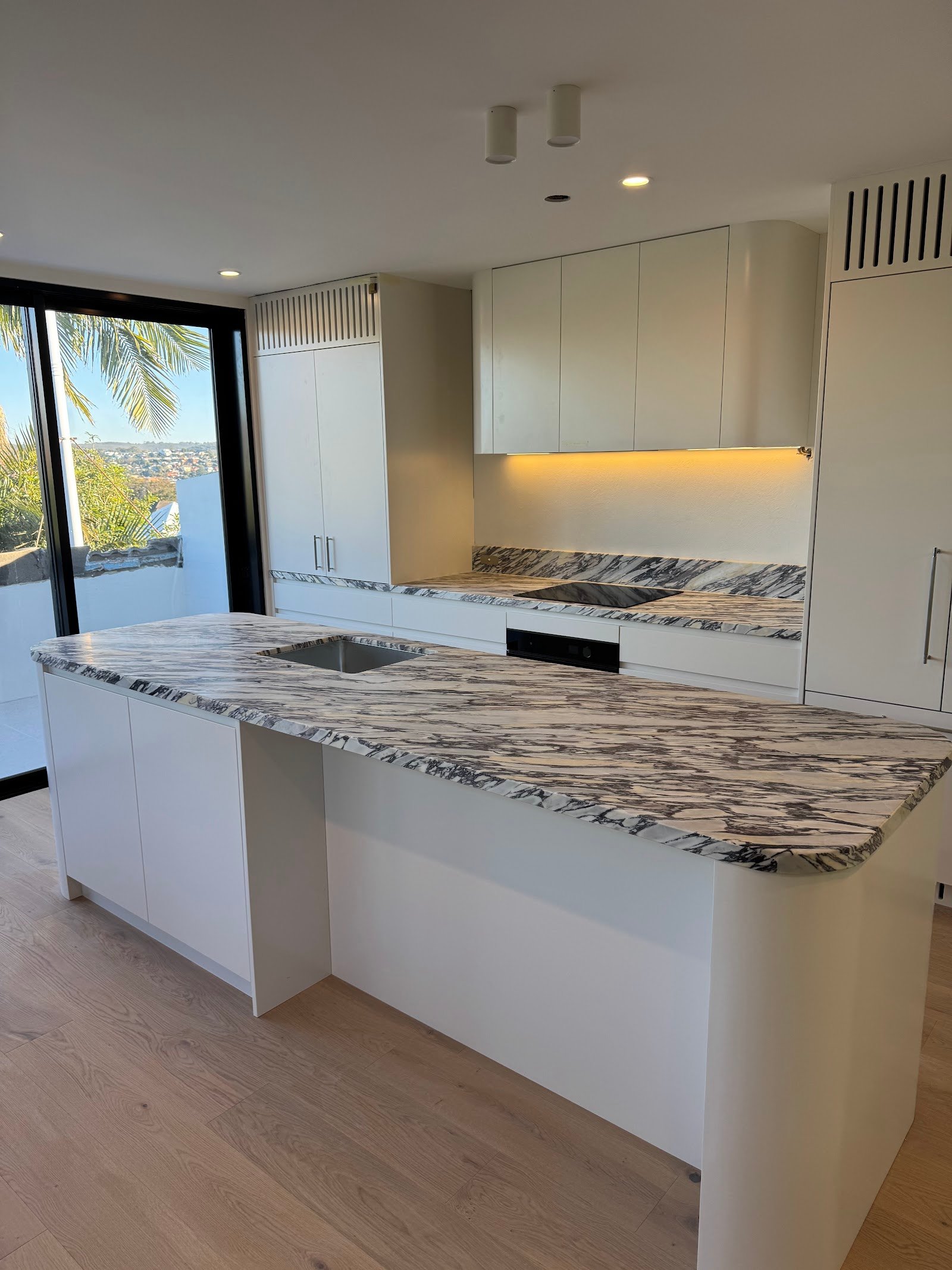 Kitchen at the Fairlight townhouse renovation with white cabinetry, marble countertops and oak flooring, Black Willow Group