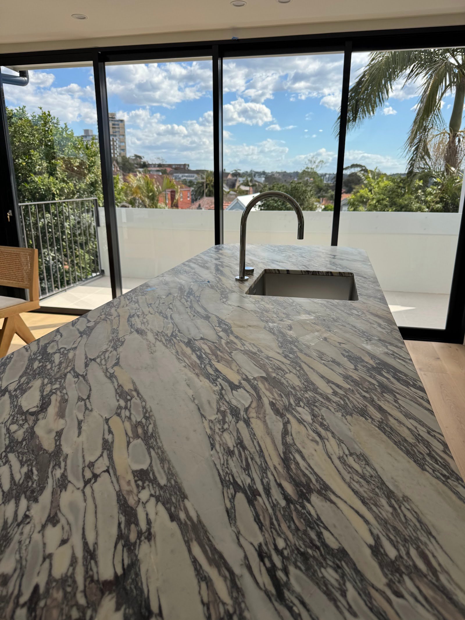 Kitchen at the Fairlight townhouse renovation showing marble island bench and floor-to-ceiling windows, Black Willow Group